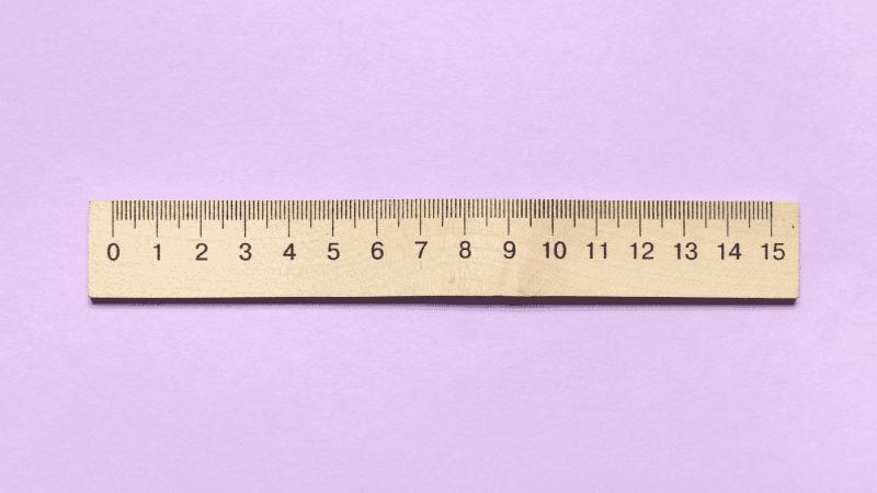 A neutral and calming educational illustration showing a simple ruler and a piece of soft string, representing a private and stress-free way to measure for the correct condom size at home