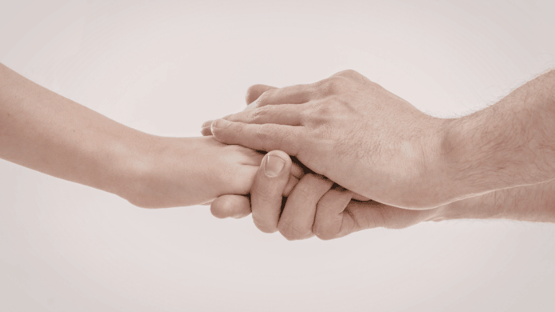 A supportive and non-explicit illustration of two people’s hands clasped together, symbolizing the emotional trust and performance confidence that comes with using a correctly fitted condom.